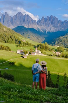 Couple viewing the landscape of Santa Maddalena Village Val di Funes, South Tyrol, Italy Dolomites, men and women visit Dolomites mountains, Val di Funes valley, Trentino Alto Adige, South Tyrol, Italy,