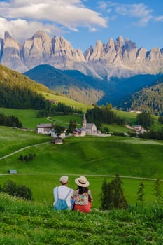 Couple viewing the landscape of Santa Maddalena Village Val di Funes, South Tyrol, Italy Dolomites, men and women visit Dolomites mountains, Val di Funes valley, Trentino Alto Adige, South Tyrol, Italy,