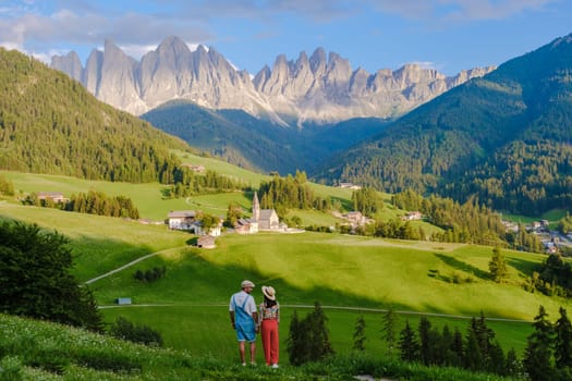 Couple viewing the landscape of Santa Maddalena Village Val di Funes, South Tyrol, Italy Dolomites, men and women visit Dolomites mountains, Val di Funes valley, Trentino Alto Adige, South Tyrol, Italy,