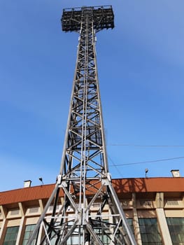 Metal tower with round spotlights for lighting a sports stadium in the city. Metal column for lighting.