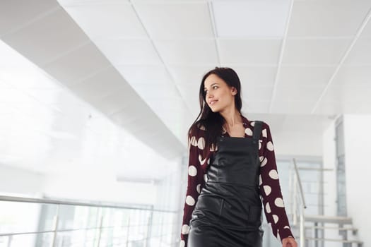 Beautiful young brunette in black skirt indoors in office or airport. Having free time.