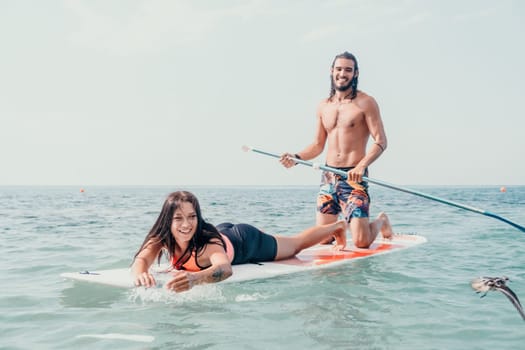 Silhouette of woman standing, surfing on SUP board, confident paddling through water surface. Idyllic sunset or sunrise. Sports active lifestyle at sea or river.