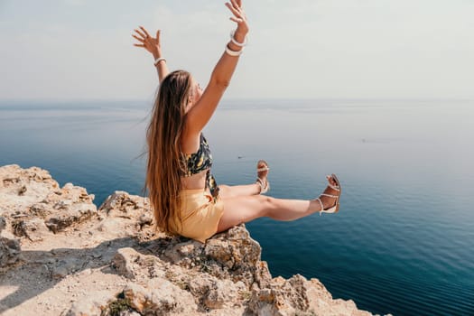 Woman travel sea. Happy tourist taking picture outdoors for memories. Woman traveler looks at the edge of the cliff on the sea bay of mountains, sharing travel adventure journey.