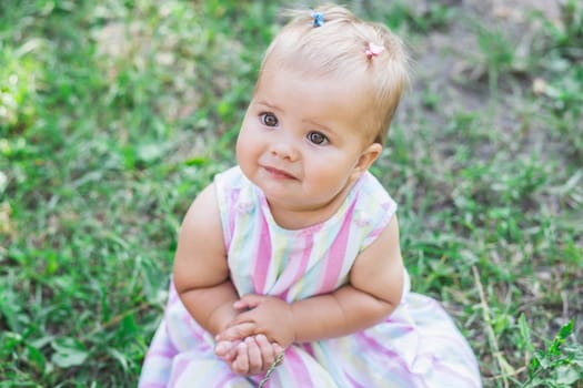 adorable baby in multicolored dress in the park.