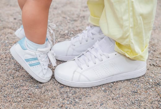 Mom and daughter are in the same white sneakers.