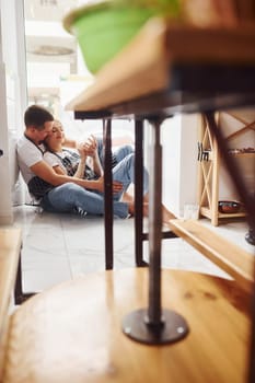 Taking a break and sitting on the floor. With her boyfriend or husband. Young female ceramist indoors with handmade clay product. Conception of pottery.