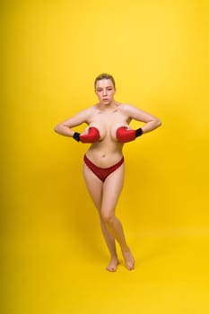 Image of seductive young woman boxer posing isolated on yellow red background in boxing gloves.