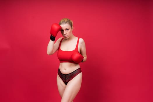 Image of seductive young woman boxer posing isolated on yellow red background in boxing gloves.