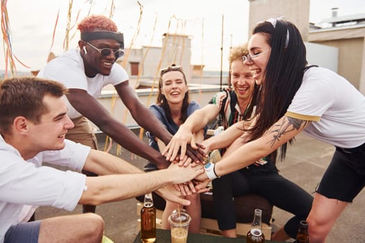 Unity of people. Group of young people in casual clothes have a party at rooftop together at daytime.