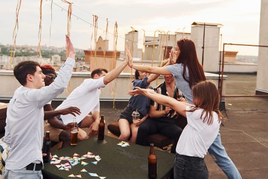 Unity of people. Group of young people in casual clothes have a party at rooftop together at daytime.