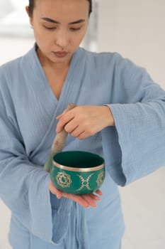 Asian woman playing Tibetan singing bowl