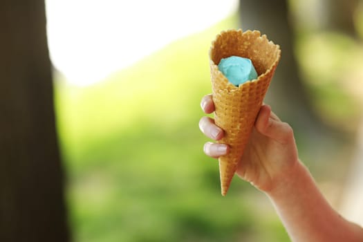 Female hand holding wafer cone with blue ice cream. Close up, High resolution product. blue ice cream in hand