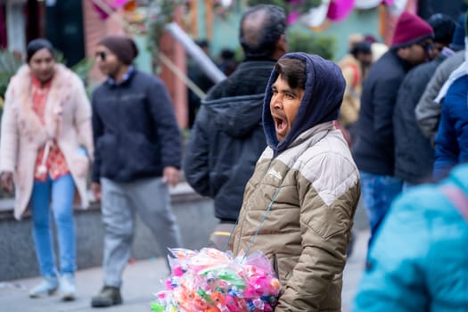 Manali, HImachal Pradesh, India - circa 2023 : Toy vendor yawning as they search for customers on the crowded mall road in Manali