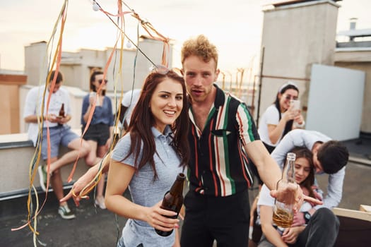 Happy couple. Group of young people in casual clothes have a party at rooftop together at daytime.