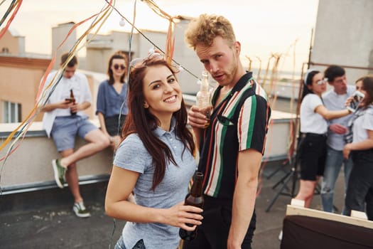 Happy couple. Group of young people in casual clothes have a party at rooftop together at daytime.