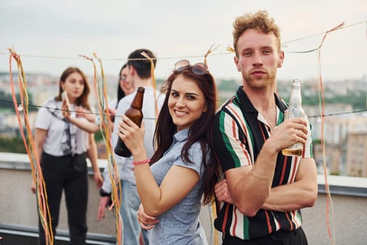 Happy couple. Group of young people in casual clothes have a party at rooftop together at daytime.