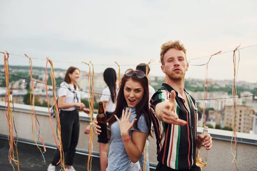 Happy couple. Group of young people in casual clothes have a party at rooftop together at daytime.