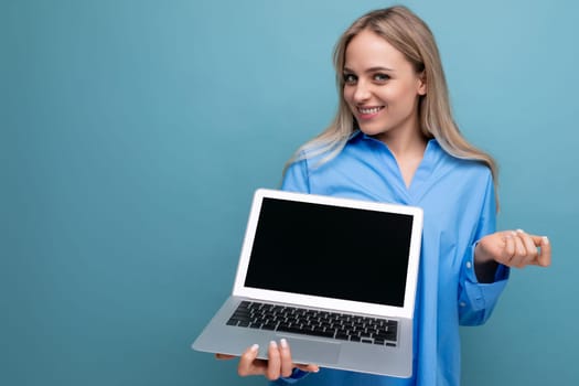 attractive blonde girl showing blank screen of portable laptop with mockup on blue background.