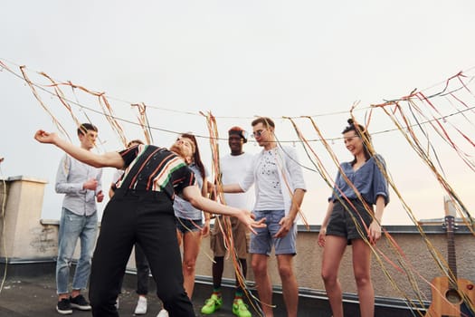 Recreation time. Group of young people in casual clothes have a party at rooftop together at daytime.