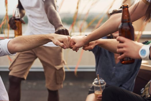 Unity of people. Group of young people in casual clothes have a party at rooftop together at daytime.