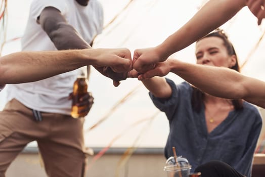 Unity of people. Group of young people in casual clothes have a party at rooftop together at daytime.