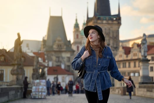 Stylish young beautiful woman earing black hat in Prague on background. Elegant retro lady fine art portrait.