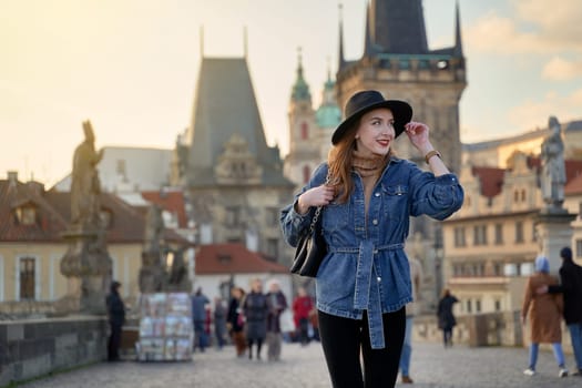 Stylish young beautiful woman earing black hat in Prague on background. Elegant retro lady fine art portrait.