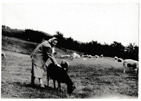 BESKYDY MOUNTAINS, THE CZECHOSLOVAK SOCIALIST REPUBLIC - JUNE 3, 1957: Retro photo shows rural woman with a black sheep. Black and white vintage photography.