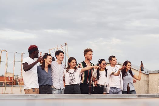 Group of young people in casual clothes have a party at rooftop together at daytime.