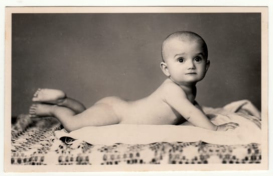 BEROUN, THE CZECHOSLOVAK REPUBLIC - AUGUST 22, 1947: Vintage photo shows naked toddler. Black and white retro photography.