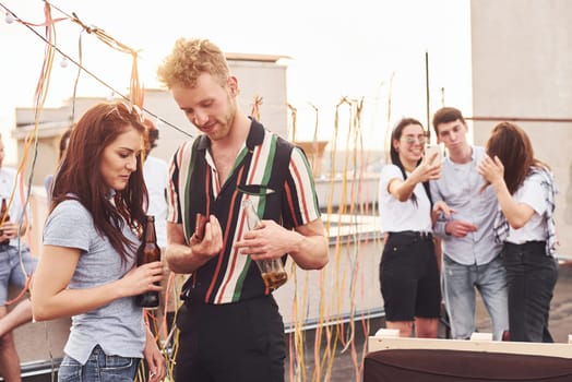 Happy couple. Group of young people in casual clothes have a party at rooftop together at daytime.