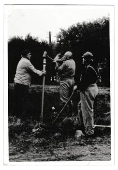 THE CZECHOSLOVAK SOCIALIST REPUBLIC - SEPTEMBER 20, 1988: Retro photo shows volunteers build a touristic sign. Black and white vintage photography