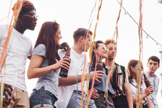 Cloudy weather. Group of young people in casual clothes have a party at rooftop together at daytime.