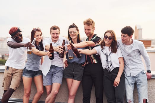 Cloudy weather. Group of young people in casual clothes have a party at rooftop together at daytime.