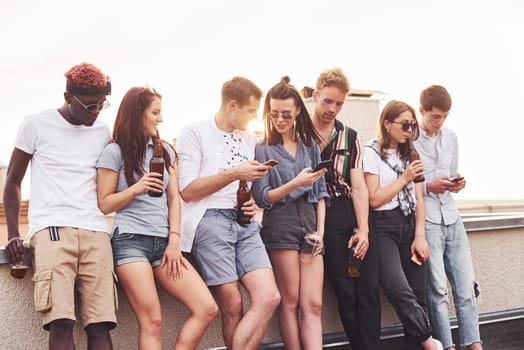 Cloudy weather. Group of young people in casual clothes have a party at rooftop together at daytime.