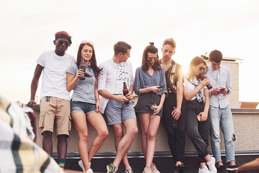 Cloudy weather. Group of young people in casual clothes have a party at rooftop together at daytime.