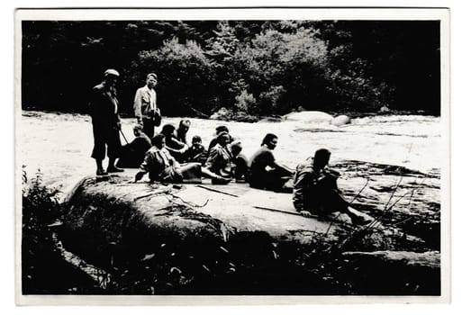 THE CZECHOSLOVAK SOCIALIST REPUBLIC - JULY 4, 1954: Retro photo shows tourists have a rest on the bank of the river. Black and white vintage photography.