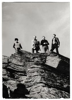 THE CZECHOSLOVAK SOCIALIST REPUBLIC - CIRCA 1980s: Retro photo shows tourists stand on top of the rock. People on holiday - vacation. Black And white vintage photography
