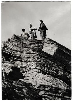 THE CZECHOSLOVAK SOCIALIST REPUBLIC - CIRCA 1980s: Retro photo shows tourists stand on top of the rock. People on holiday - vacation. Black and white vintage photography