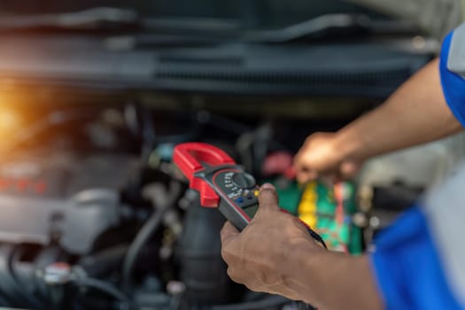 Close up technician uses multimeter voltmeter to check voltage level in car battery. Service and Maintenance car battery..