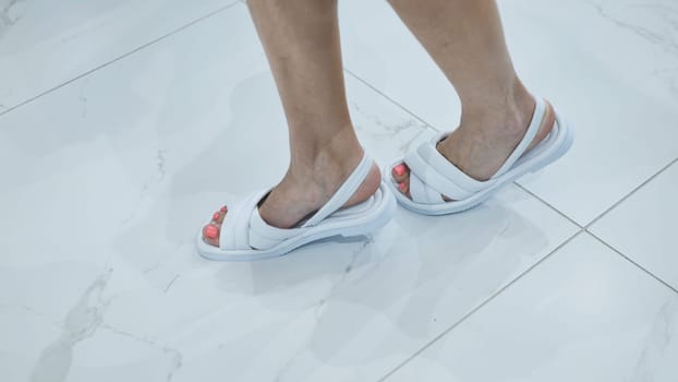 Girls trying on white summer sandals in the store