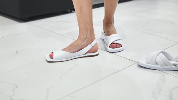 Girls trying on white summer sandals in the store