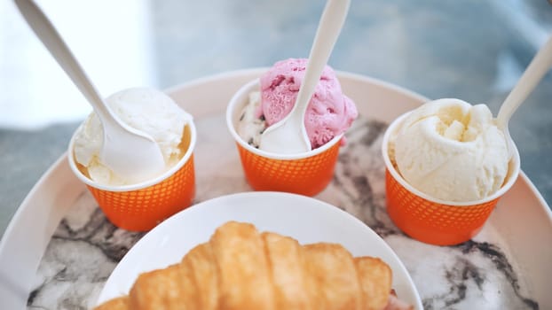 Ice cream and croissant with meat on the plate at the cafe