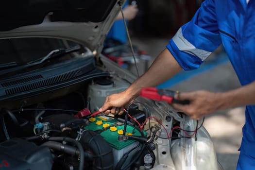 Close up technician uses multimeter voltmeter to check voltage level in car battery. Service and Maintenance car battery..