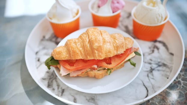 Ice cream and croissant with meat on the plate at the cafe