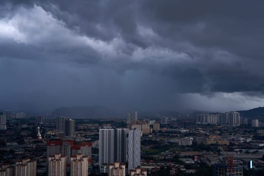A black storm cloud of rain over the town. Bad weather conditions. Kuala Lumpur, Malaysia - 11.11.2022