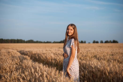Portrait of a beautiful girl in field of ripe wheat lit by warm rays of setting sun