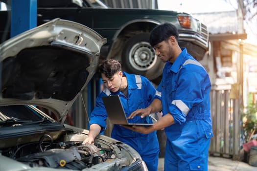 Mechanic man shows report to the asian coworker at garage, A man mechanic and his son discussing repairs done vehicle. Changing automobile business..