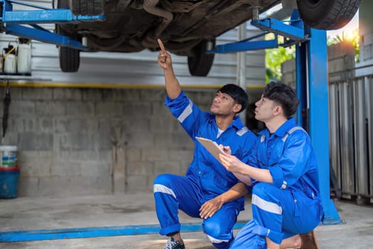 Mechanic man shows report to the asian coworker at garage, A man mechanic and his son discussing repairs done vehicle. Changing automobile business..