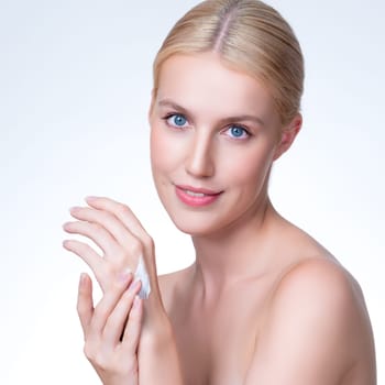 Personable woman applying moisturizer cream on her hand for perfect skincare treatment concept in isolated background. Beauty care cream applying on body by female model with soft natural makeup.